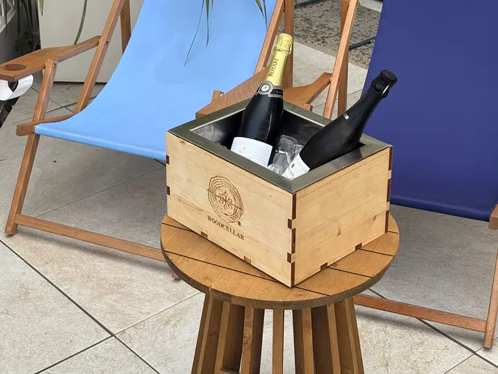Glacetta Wood Cellar con due bottiglie di spumante su un tavolino di legno, davanti a due sdraio.