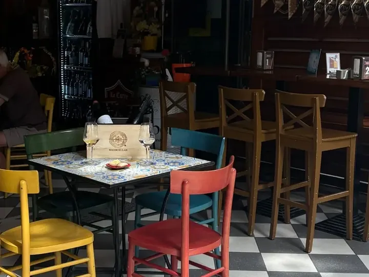 Tavolo di maioliche con la glacetta Wood Cellar e due calici di vino bianco, nella sala di un'enoteca.
